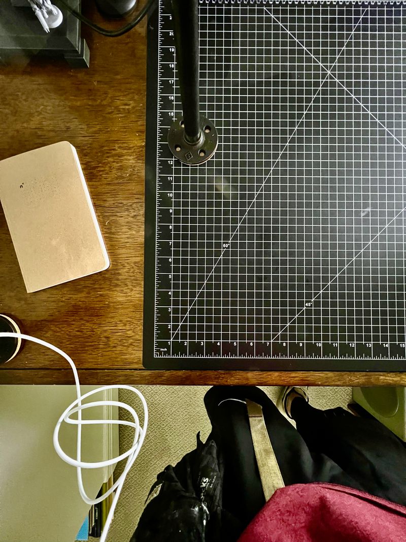 A massive black cutting mat on desk wood with a 1 inch grid.