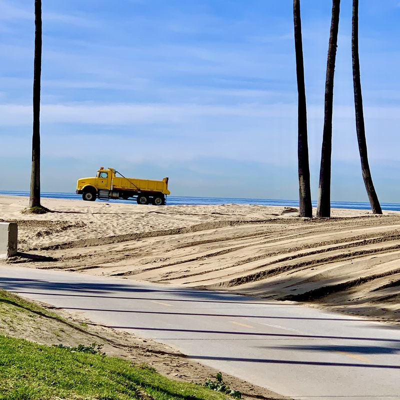 A yellow haul truck on the beach.